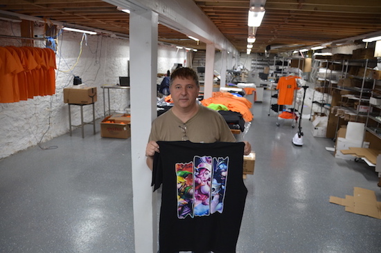 Ken Daluisio holds a T-shirt with a four-color design that was printed in the basement of The Print Shop.