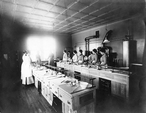 Another image shows the women receiving instruction in “domestic science” taught by Mrs. Ruth Webster Howard. The House of Refuge had both gas ranges and coal/wood stoves to prepare women for work in homes with either setup. The final image shows a group of children, those born to “inmates” at the House of Refuge. 