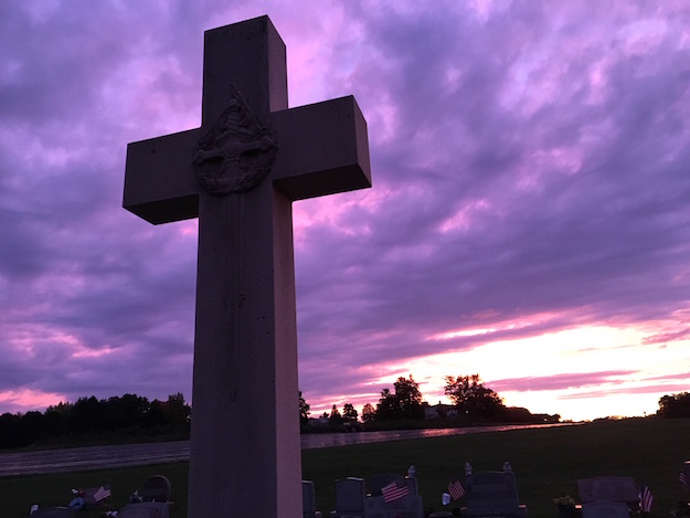   The cross at the Cook grave at Hillside Cemetery is pictured at sunset on Saturday.