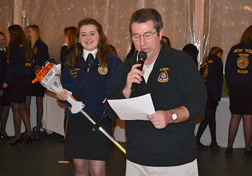 File photo by Tom Rivers:  Barry Flansburg, president of the Albion Alumni FFA, leads an auction to benefit the FFA. Jenny McKenna of Albion holds one of the items up for bid during this photo from March 2015 during the annual Farmer-to-Neighbor night.